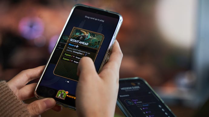 Somebody using a phone to play a card in fantasy game Sunderfolk