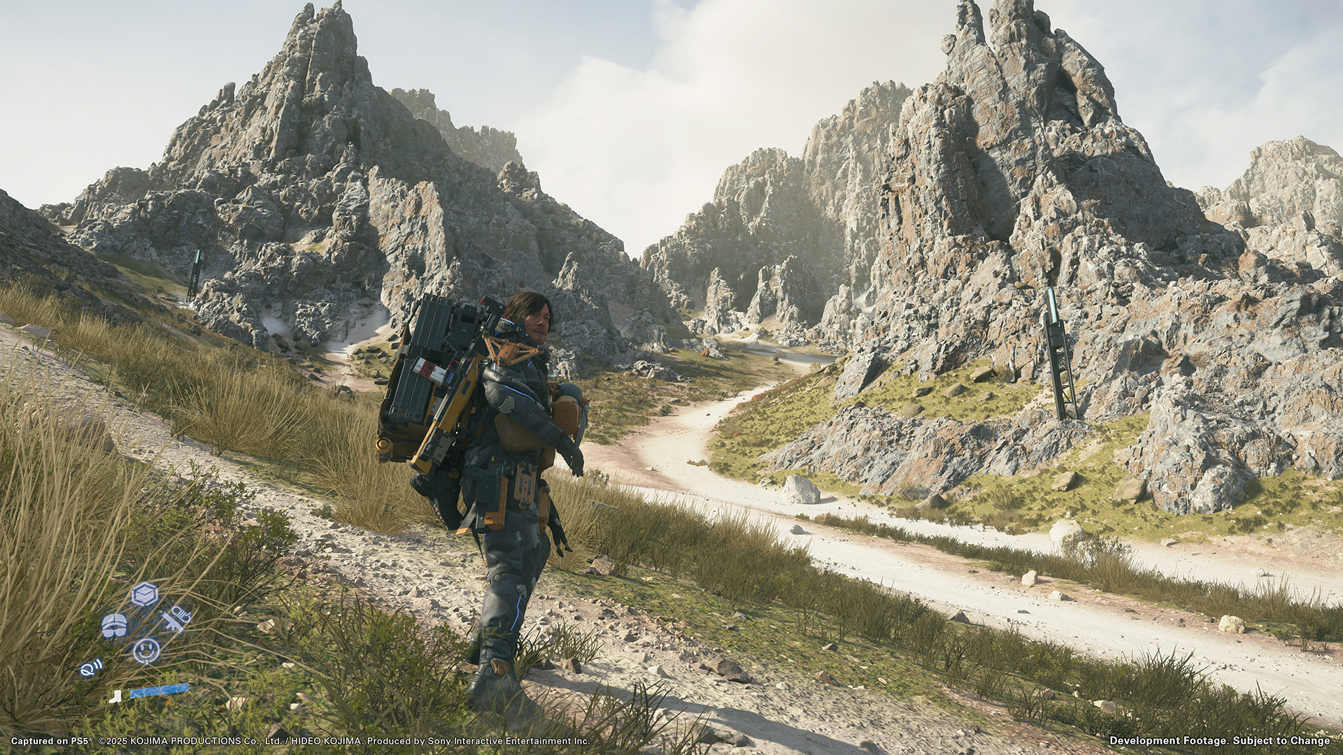Sam Bridges stands before a rugged mountain landscape in Death Stranding 2