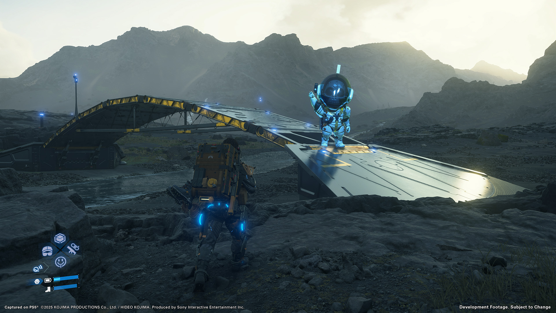 Sam approaches a bridge over a river and a robotic figure waves from the bridge in Death Stranding 2